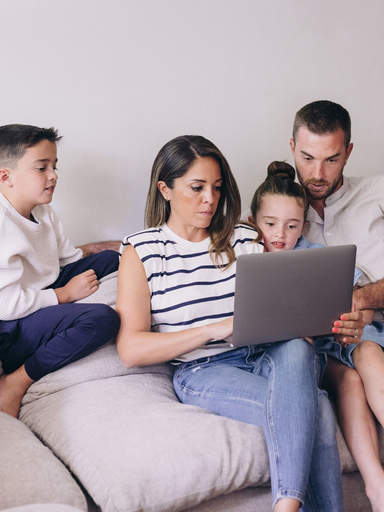 Family creating a sendmoments photo book together on a laptop