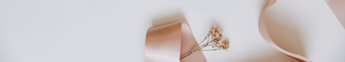 An arrangement of ribbon and dried flowers in shades of pink