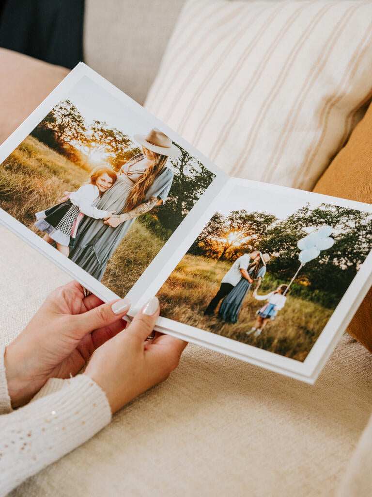 Hands holding an open photo book with family photos