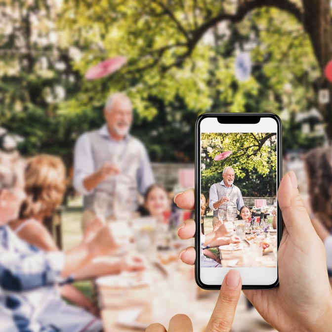 A woman photographing a celebration and saving it straight to the digital photo album on her phone