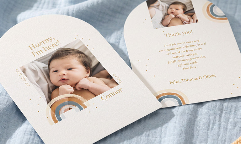 An arched baby thank you card with a newborn photo and a rainbow, next to its thank you text