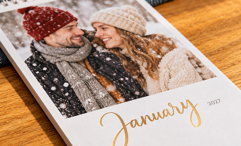 A photo calendar page with a winter photo of a couple and January in gold foil