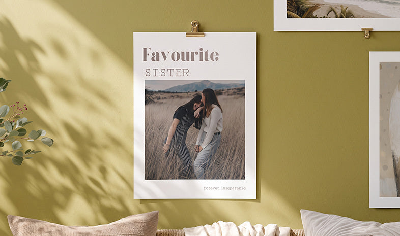 A photo poster reading Favourite Sister clipped to a green wall
