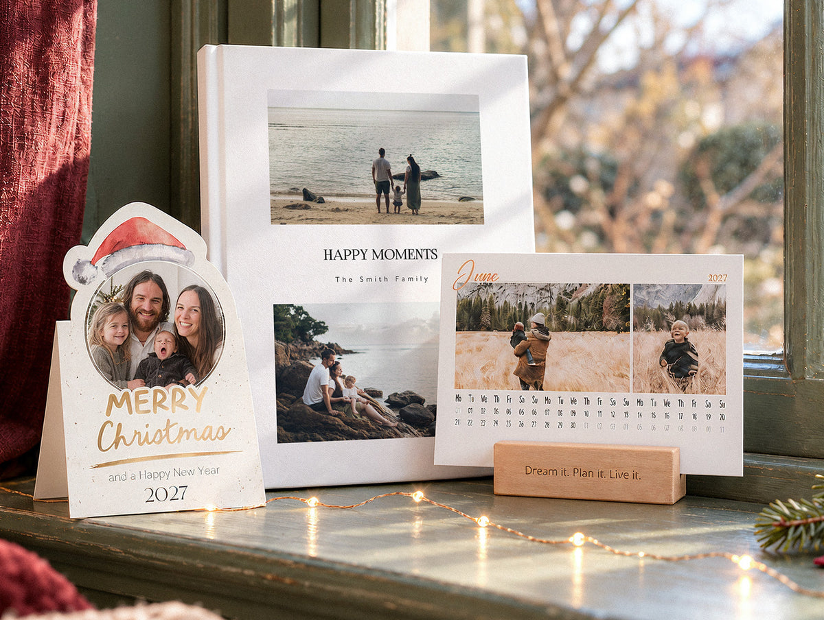 A Merry Christmas photo card, a photo book and a desk calendar on a festive windowsill