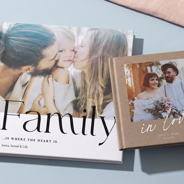A family photo book next to a couple photo book on a blue table