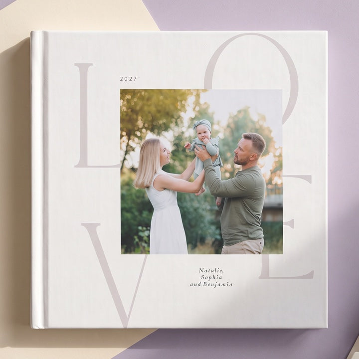 A family photo book with a large LOVE cover and a photo of parents with their baby