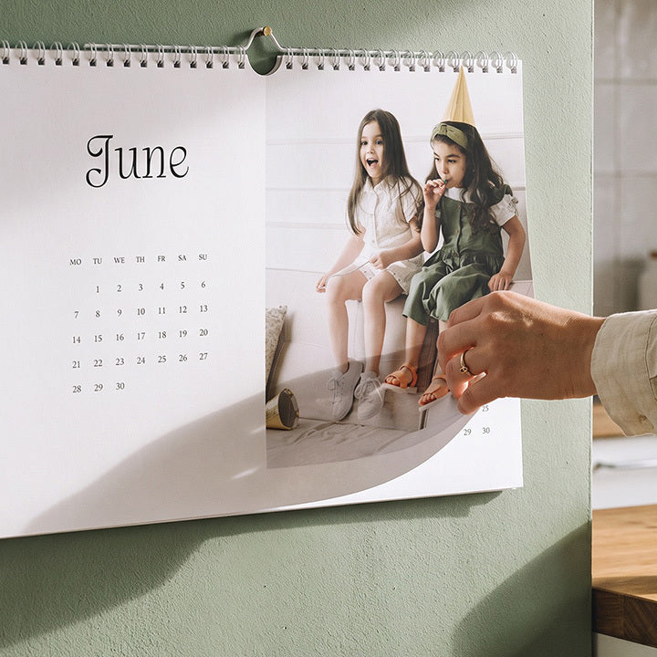 A photo wall calendar with two little girls, open at June